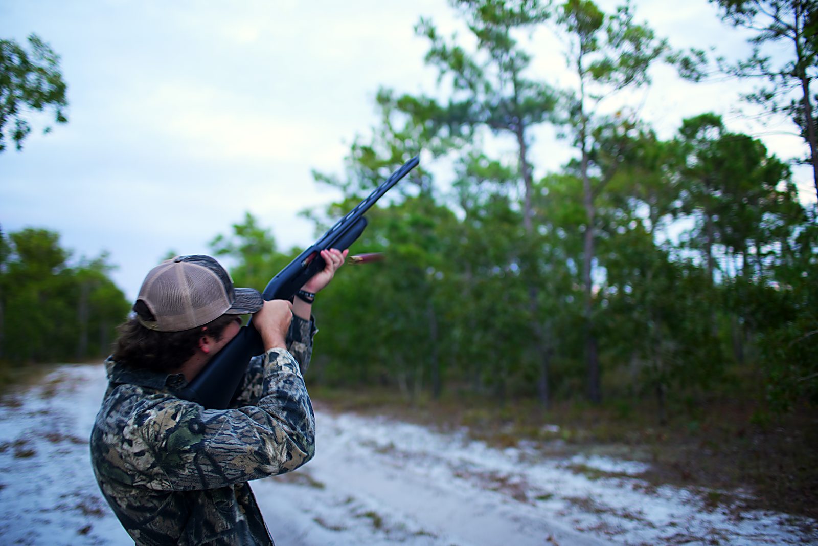Hunting photo near Wilmington, North Carolina: Tanner swinging a shotgun skyward on a sand road