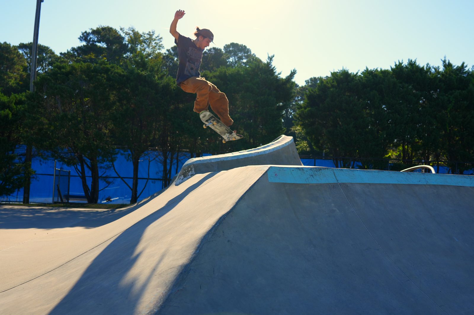 Skateboarding photo in Wilmington, NC: skater floating an air over the hip, backlit by the sun