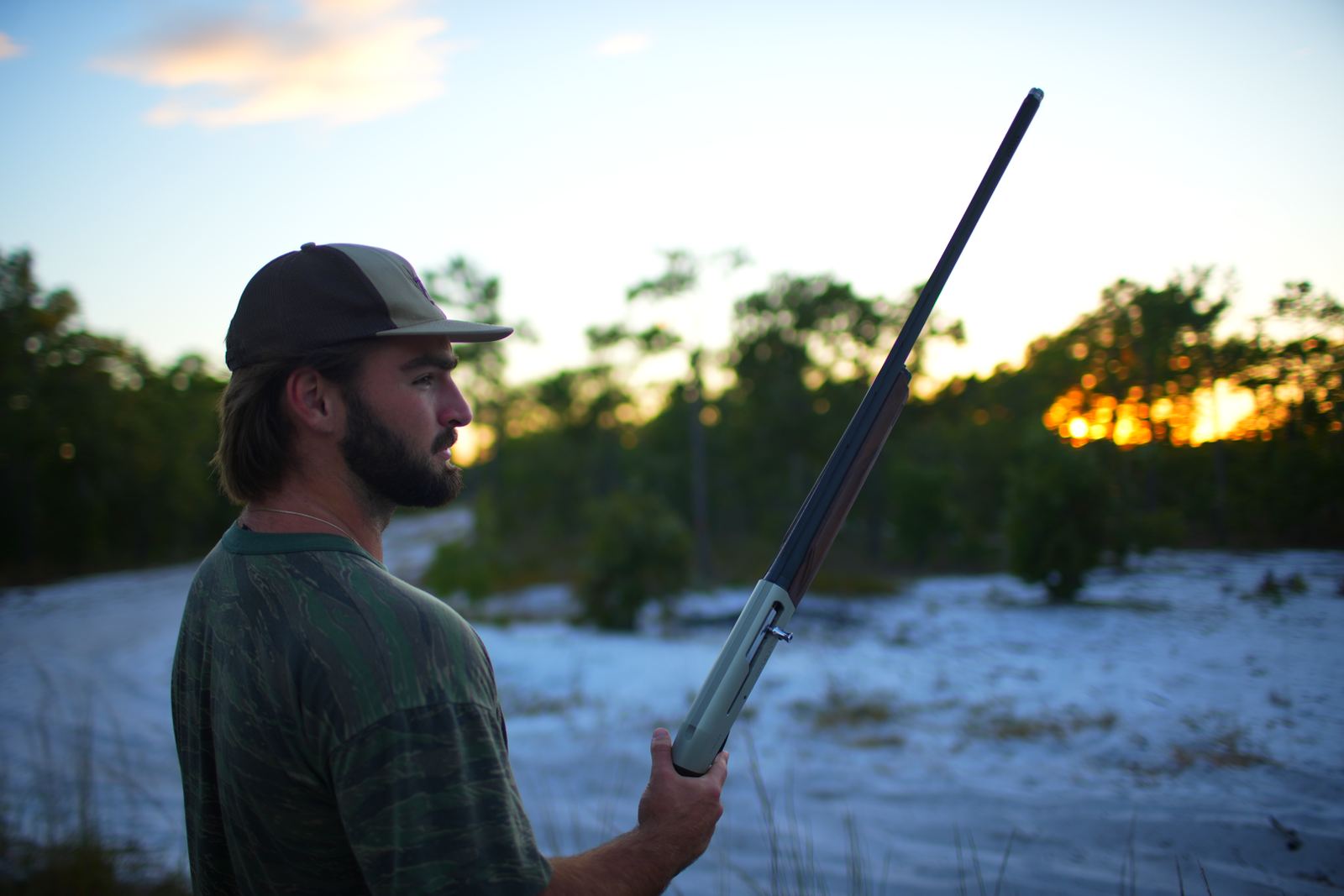 Turner silhouetted against the sunset with a shotgun over his shoulder