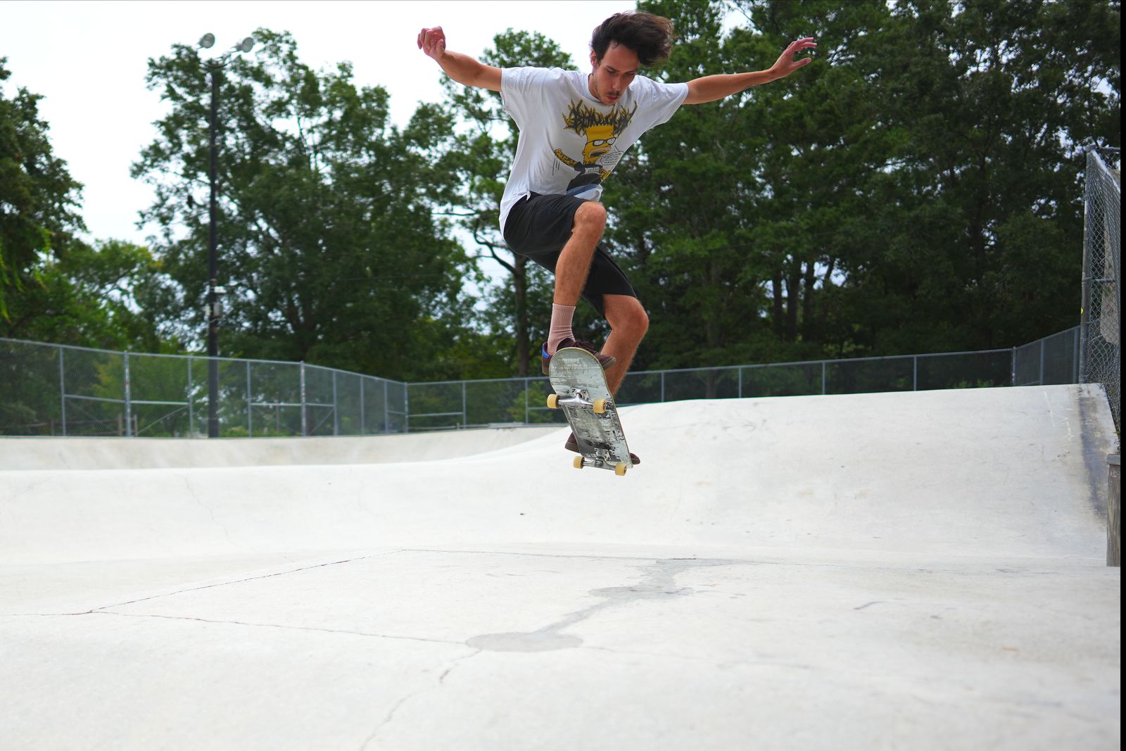 Jaden ollieing over the bank, arms out, from below
