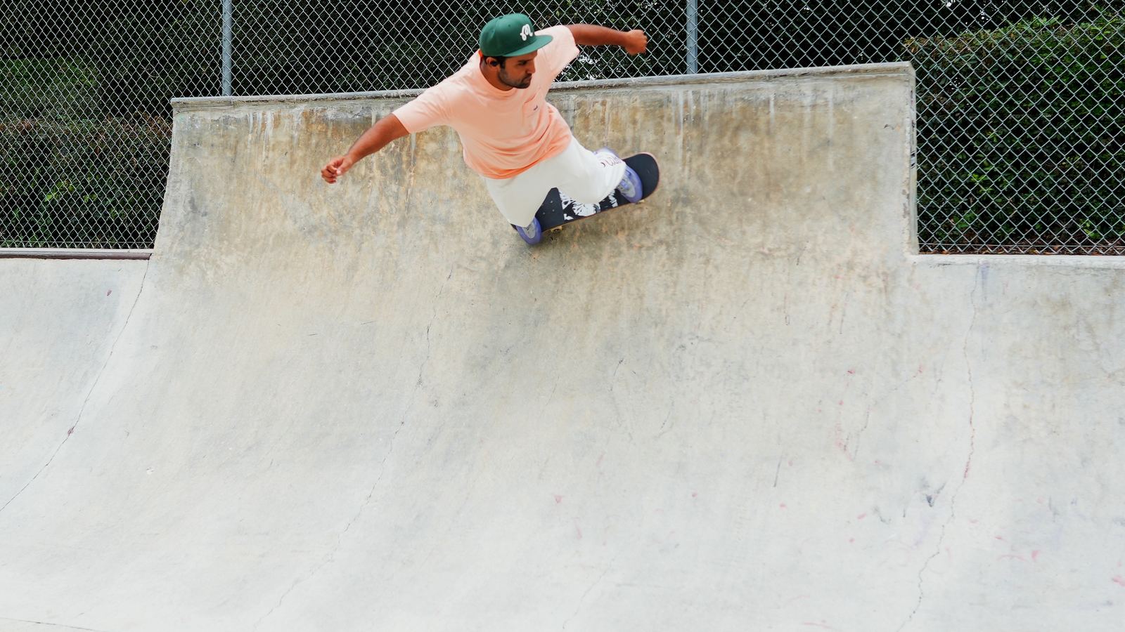 Jett Sinn in an orange shirt pivoting on the top of a concrete bank