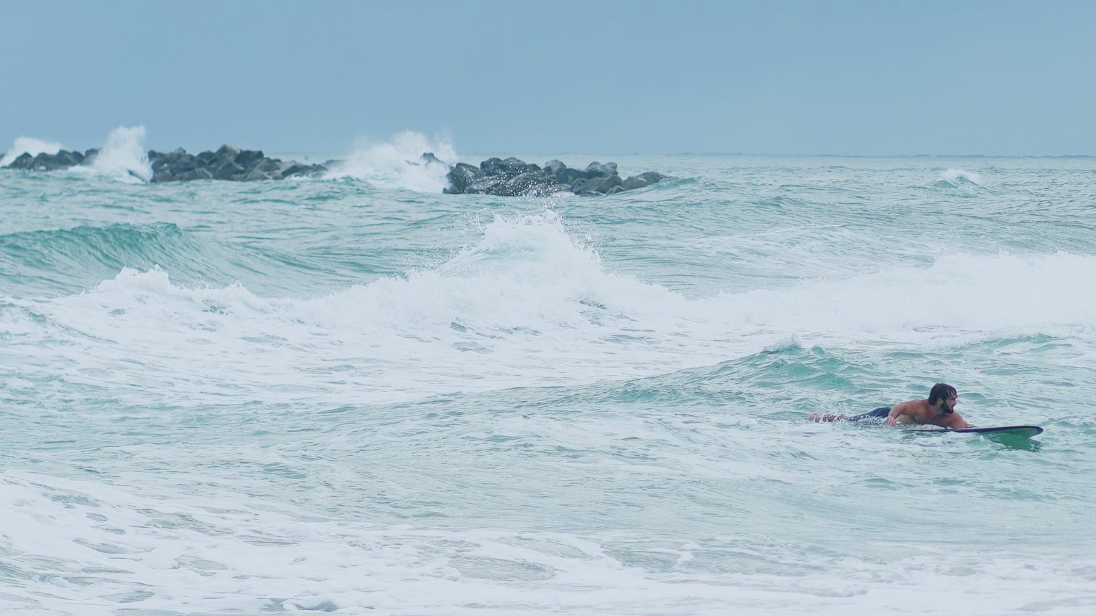 Turner coasting on his board beneath the jetty as whitewater rolls through