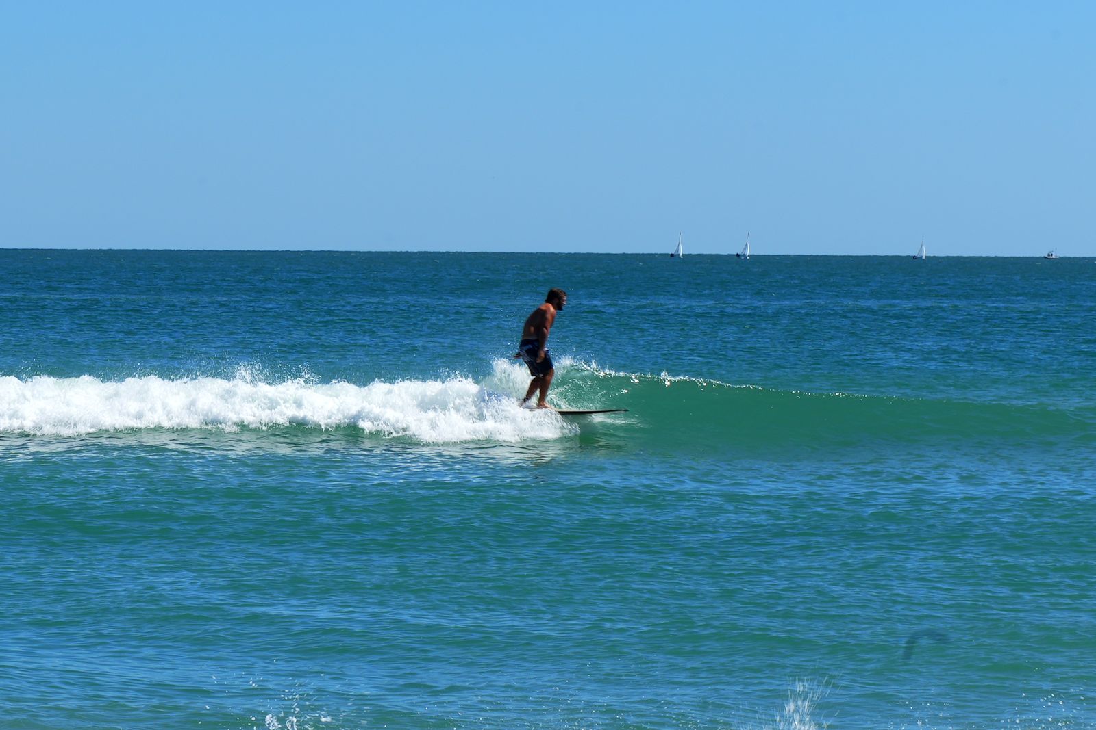 Turner gliding on a small wave with deep blue water behind
